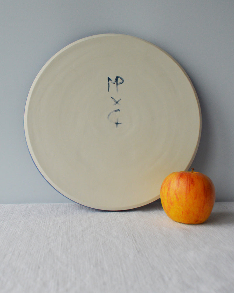Porcelaine fabriquée en France, dos de grande assiette bleue sur fond blanc