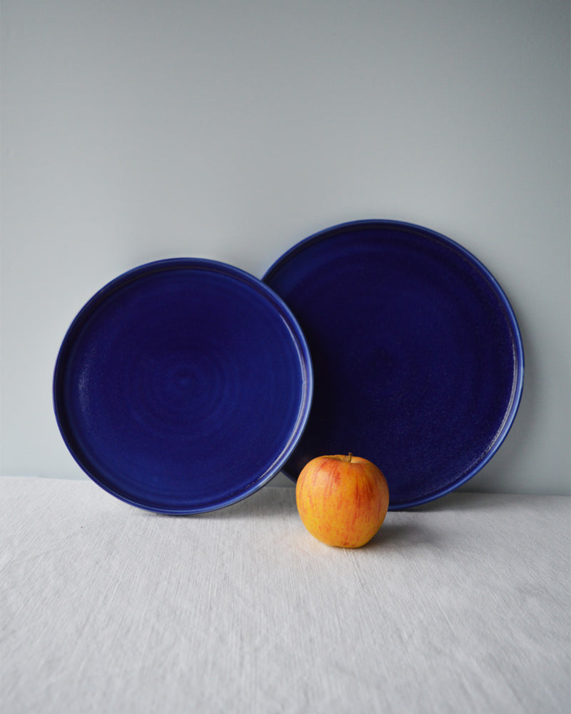 Porcelaine fabriquée en France, grande assiette et assiette à dessert bleues sur fond blanc