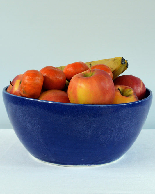 Porcelaine fabriquée en France, grand saladier bleu Primavera rempli de fruits sur fond blanc