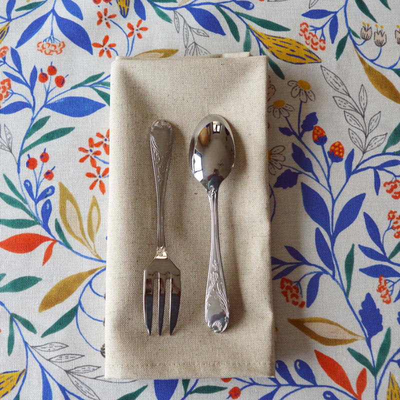 Cuillère et fourchette à dessert Guy Degrenne en inox, chinés par Maison Primavera, sur une serviette naturelle