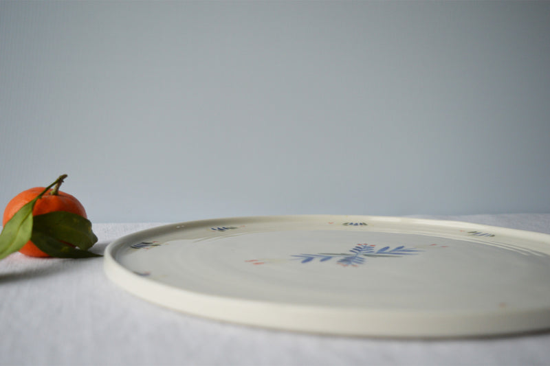 Porcelaine fabriquée en France, zoom sur plat de service rond à motif Primavera sur fond blanc