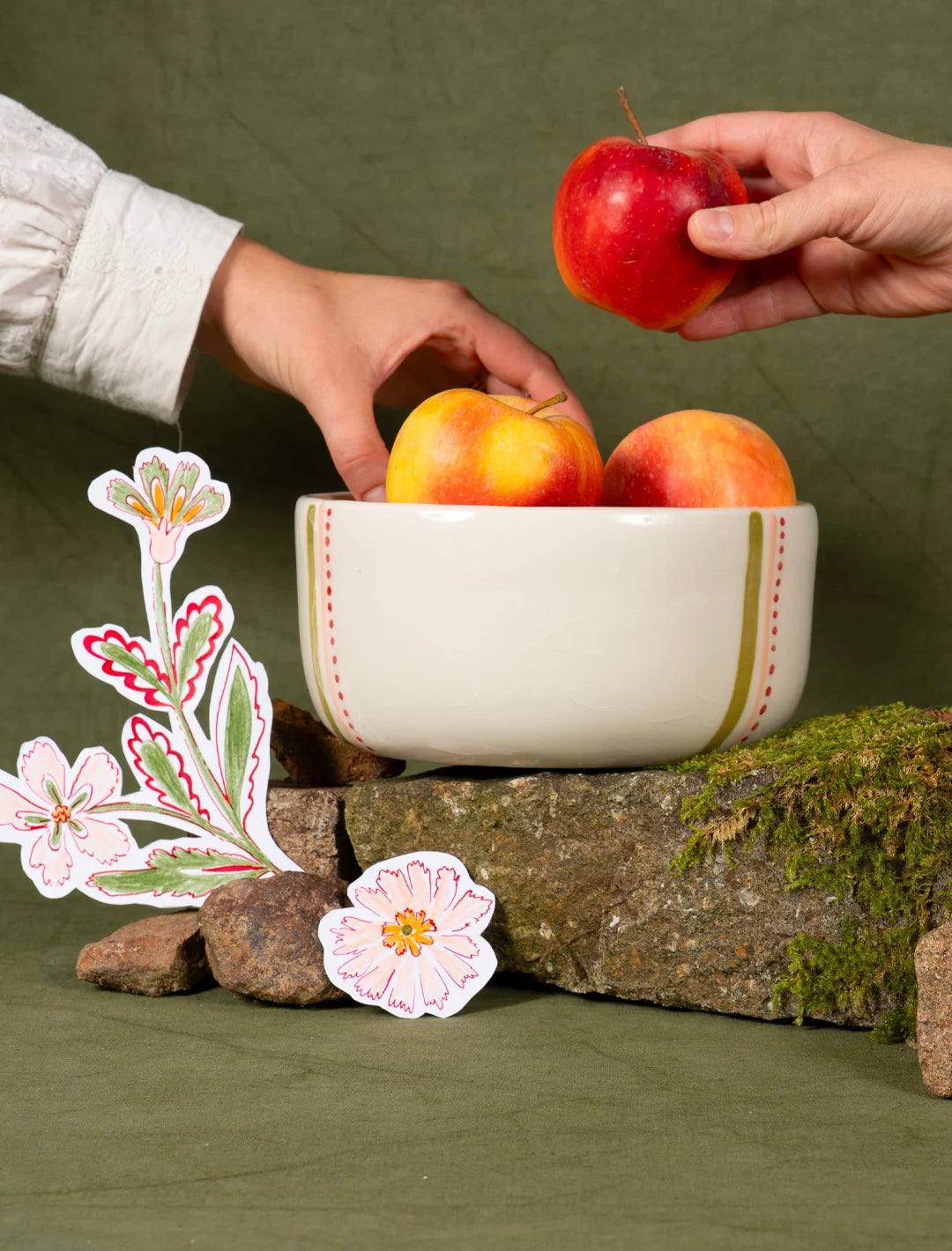 Saladier en porcelaine artisanal fabriqué en France, motif de rayures vertes, roses et rouges, rempli de pommes