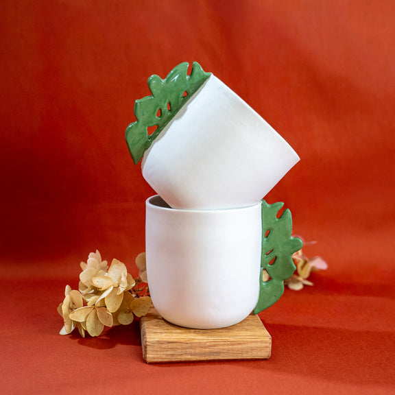 Tasses à thé blanches en porcelaine, fabriquées en France, avec anse verte motif cœur alsacien, empilées