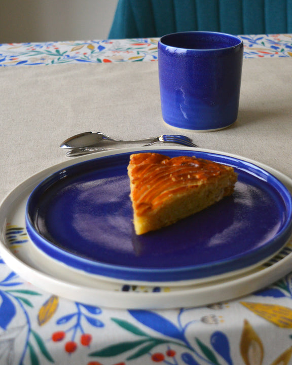 Porcelaine artisanale fabriquée en France, tasse à thé bleue Maison Primavera avec assiettes à motif et bleue sur linge de table français.