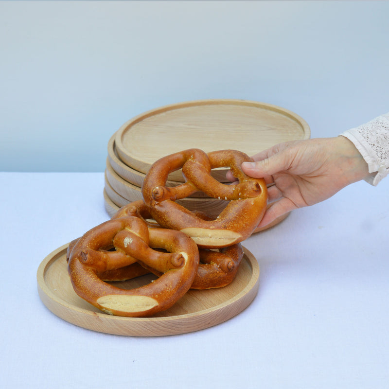 Pile d'assiettes en bois tournées à la main, fabriquées en France en Alsace, tournage sur bois artisanal. Bretzels.