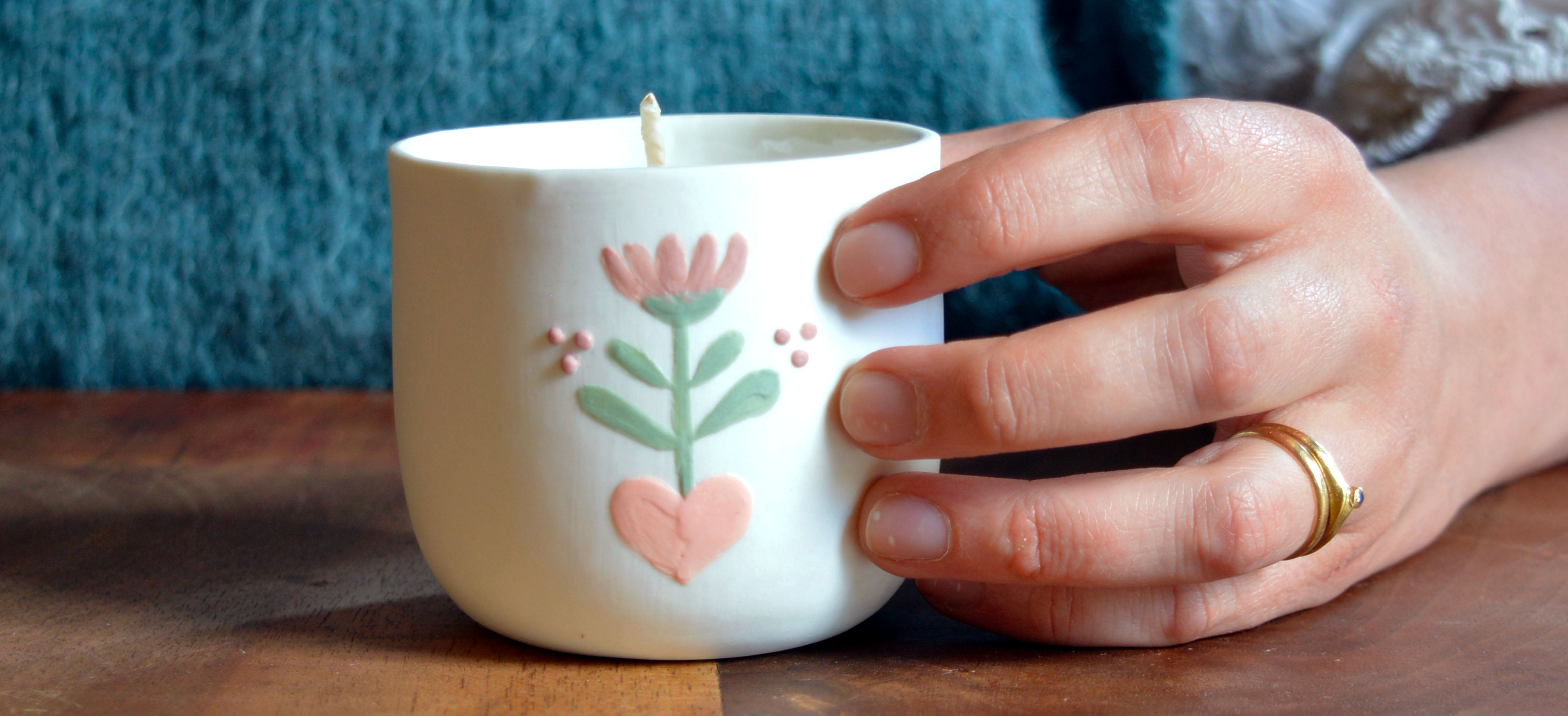 Main qui tient une bougie artisanale fabriquée en France à la main, en porcelaine, pièce unique, motif floral
