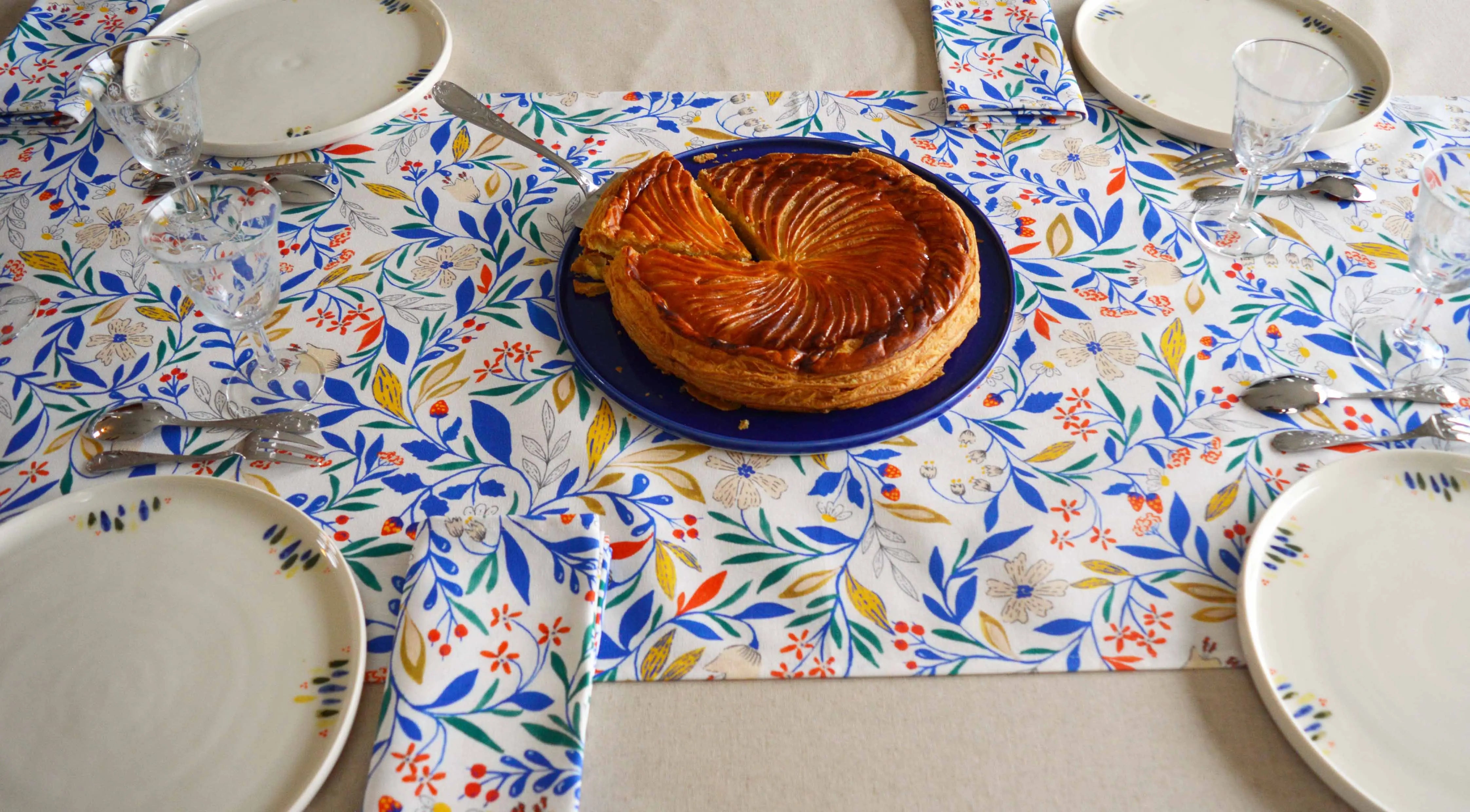 Table dressée avec linge de table français à motif et uni, céramique en porcelaine artisanale à motif et bleue