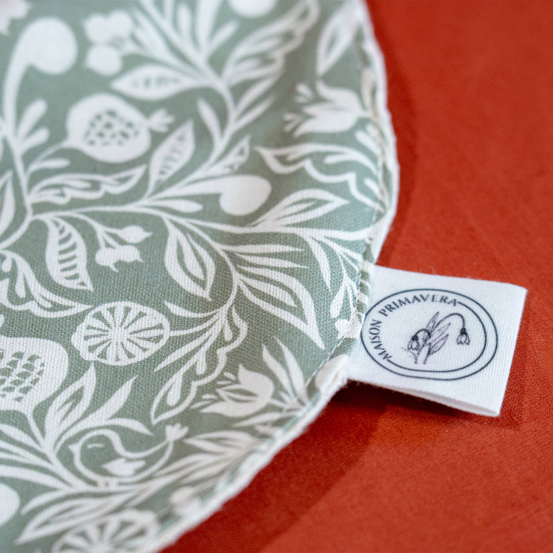 Détail du bavoir vert et blanc fabriqué en France, en coton et en lin, avec motif floral, polychrome alsacien