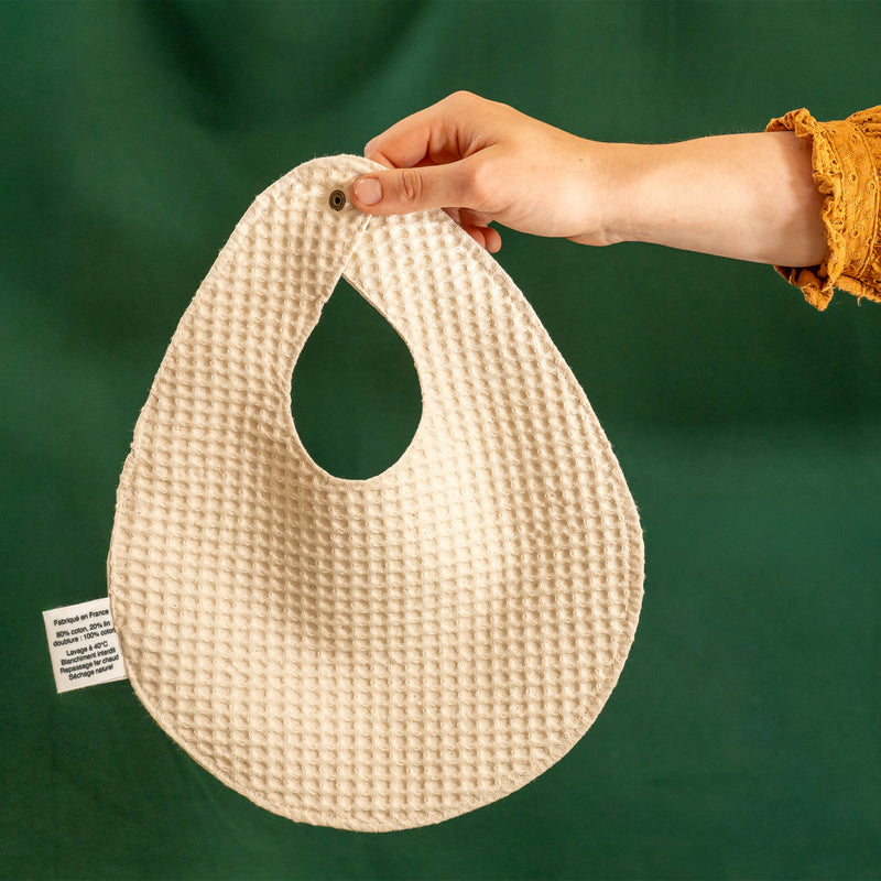 Dos d'un bavoir beige et blanc fabriqué en France, en nid d'abeille, en coton et en lin, avec motif floral, arbre de vie alsacien