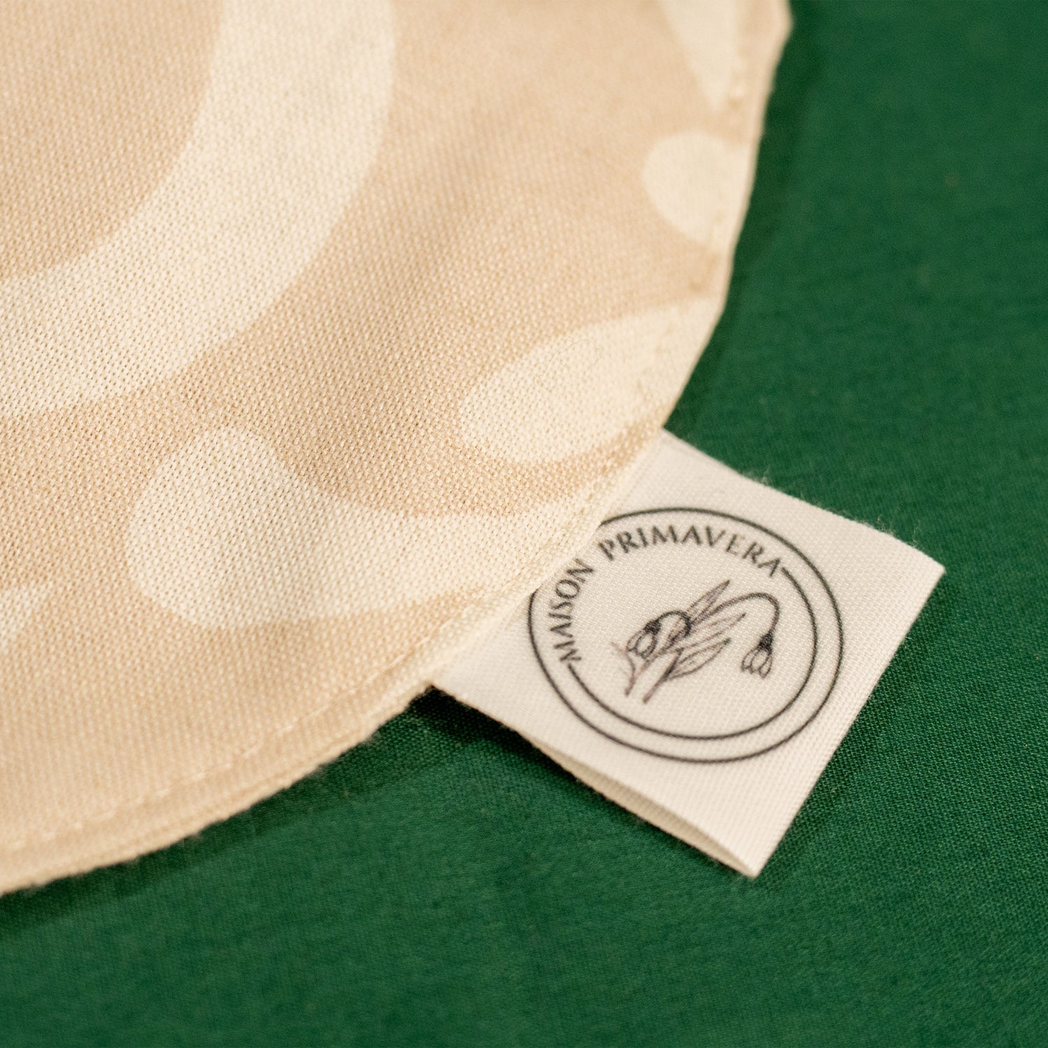 Détail d'un bavoir beige et blanc fabriqué en France, en coton et en lin, avec motif floral, arbre de vie alsacien