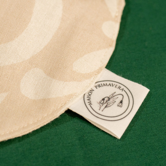 Détail d'un bavoir beige et blanc fabriqué en France, en coton et en lin, avec motif floral, arbre de vie alsacien