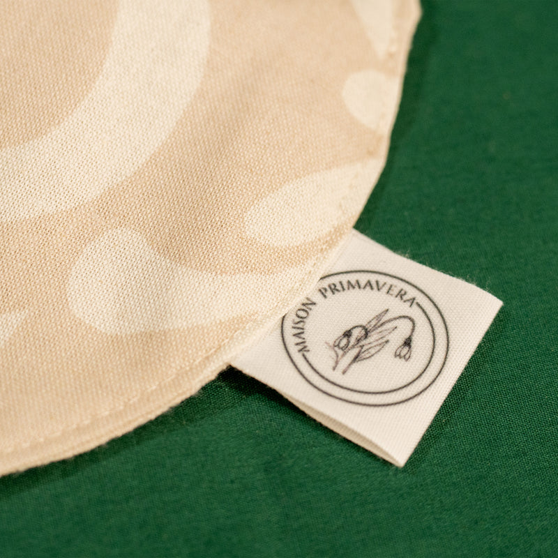 Détail d'un bavoir beige et blanc fabriqué en France, en coton et en lin, avec motif floral, arbre de vie alsacien