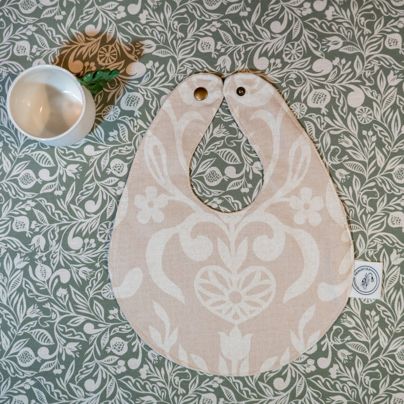 Bavoir beige et blanc fabriqué en France, en coton et en lin, avec motif floral, arbre de vie alsacien, nappe verte motif floral, tasse en porcelaine artisanale