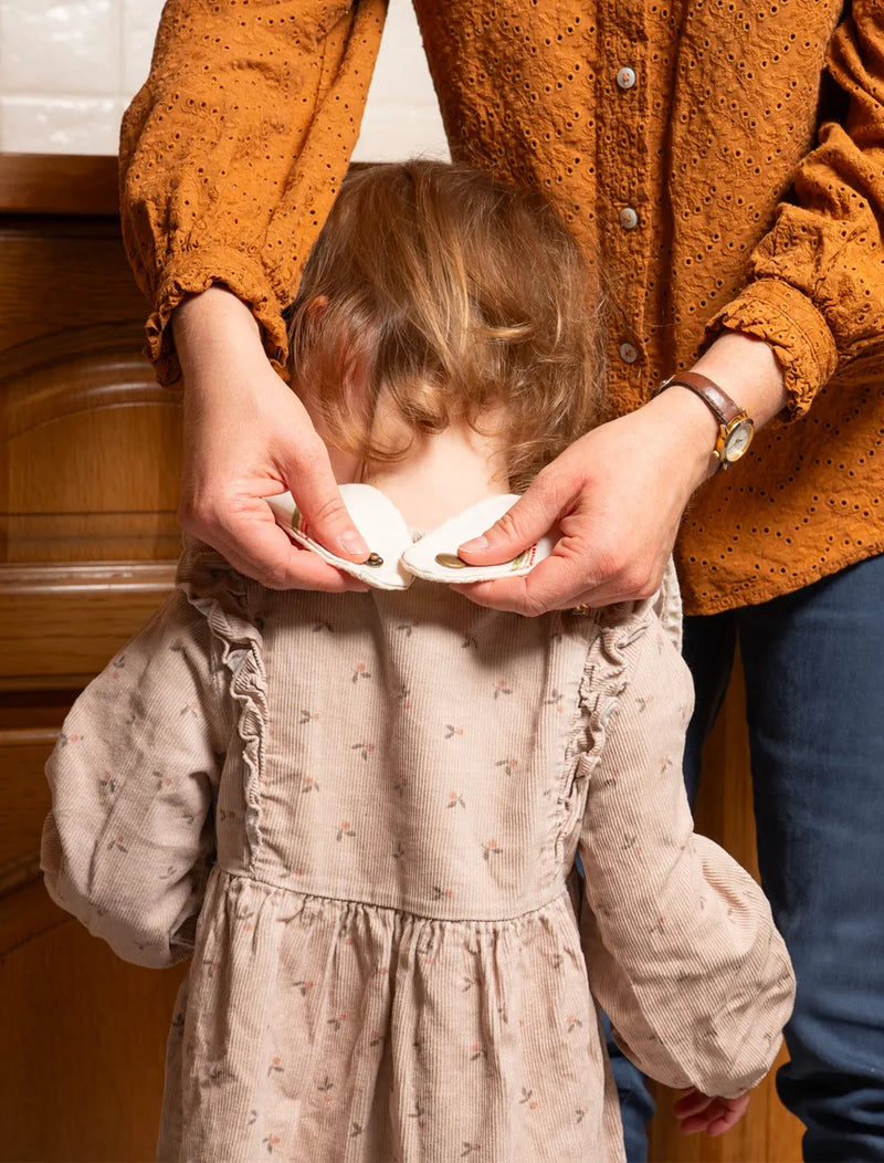 Fermeture d'un bavoir en coton et lin fabriqué en France, sur la nuque d'une petite fille