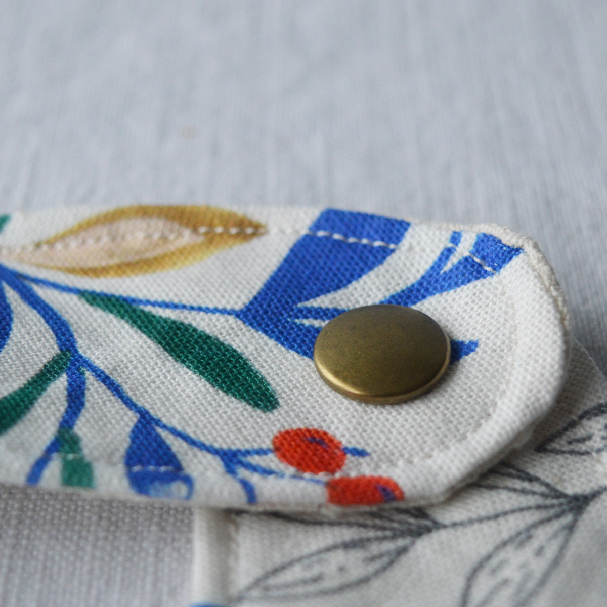 Bouton du bavoir en coton et lin à motif Primavera, tissé et fabriqué en France, sur fond blanc
