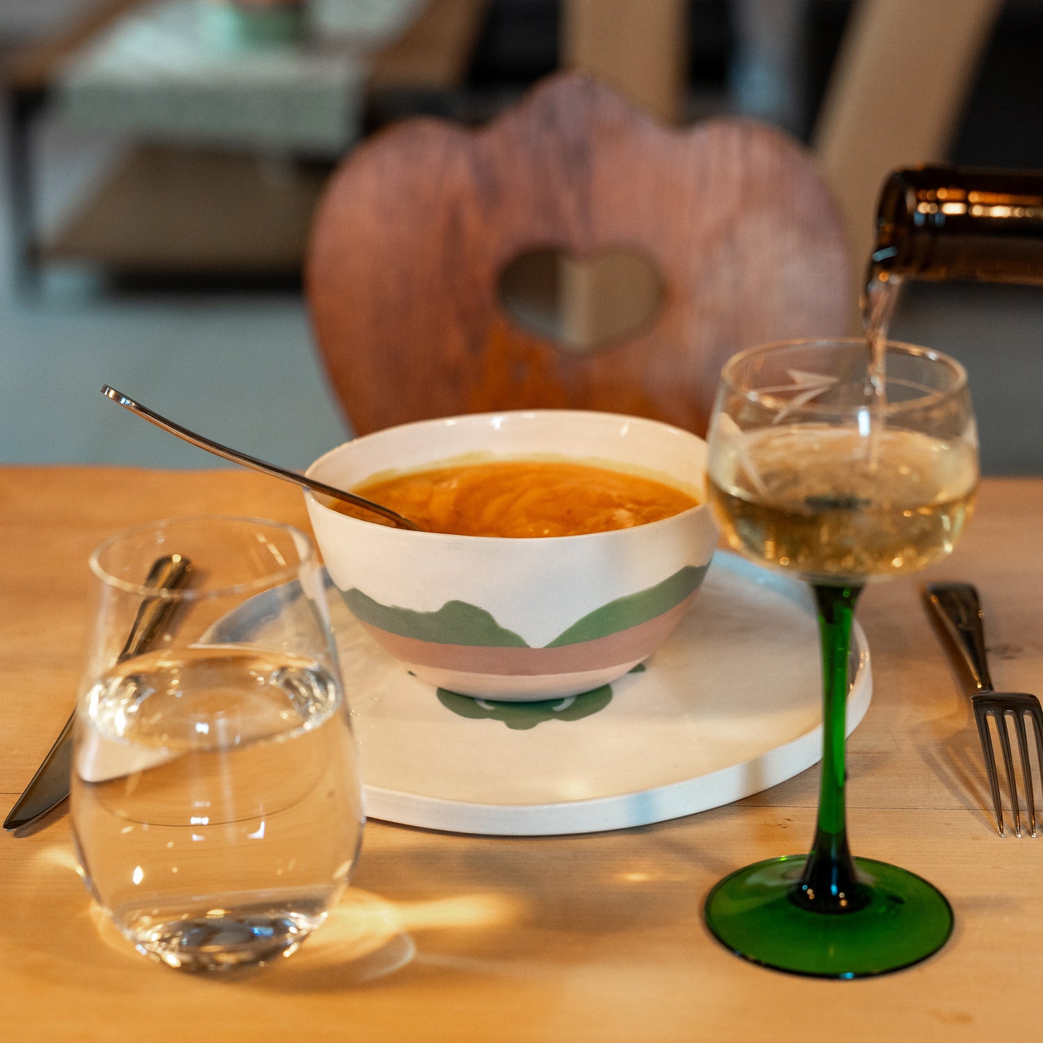 Bol en porcelaine fabriqué en France, artisanal, motif de montagnes, des Vosges, couleurs douces, rempli de soupe avec verre à vin sur table en bois