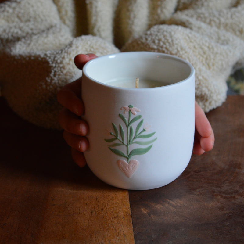 Bougie artisanale coulée dans une tasse à thé en porcelaine, fabriquée en France, senteur de Noël, décor unique Alsace, entre mains d'enfant