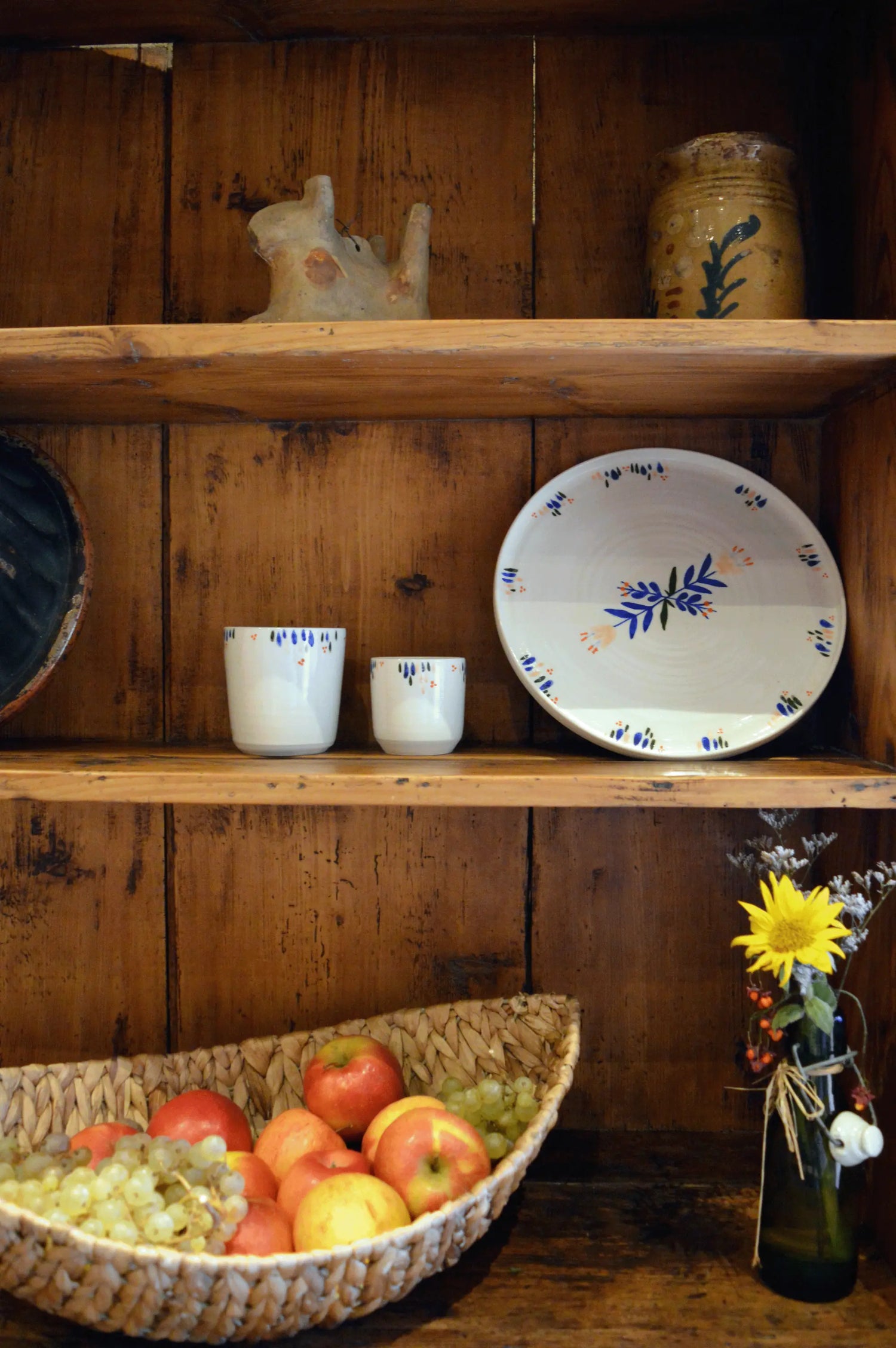 Vaisselle artisanale française en porcelaine, à motif coloré, dans un buffet