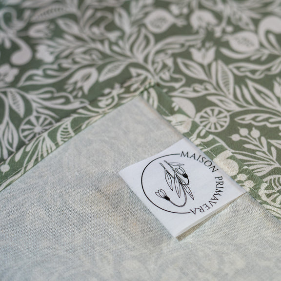 Détail étiquette de chemin de table fabriqué en France, vert et blanc, en coton et lin, motif floral polychrome alsacien
