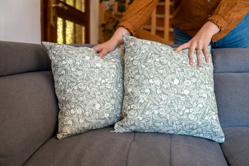 2 coussins verts et blancs fabriqués en France, en coton et lin, motif floral polychrome alsacien, fermeture zip, sur un canapé gris