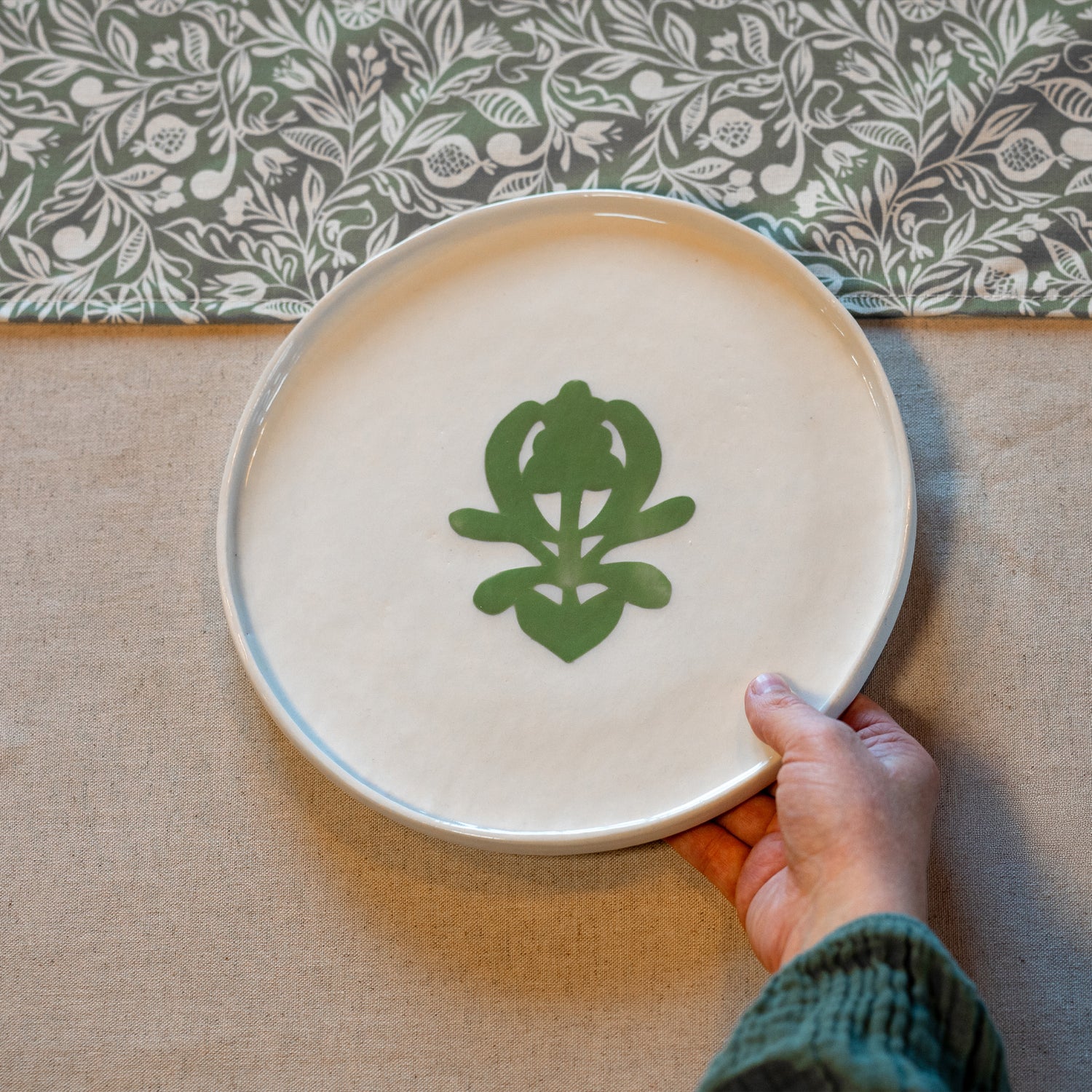 Grande assiette en porcelaine fabriquée en France, artisanale, blanche à motif vert cœur alsacien, sur linge de table made in France