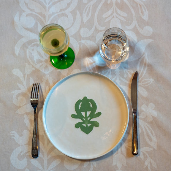 Grande assiette en porcelaine fabriquée en France, artisanale, blanche à motif vert cœur alsacien, avec verre de vin d'Alsace et couverts, nappe made in France