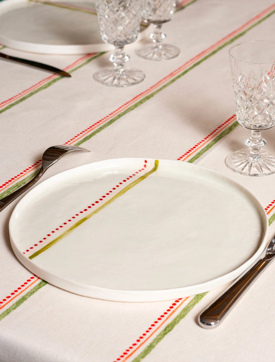 Grande assiette en porcelaine artisanale fabriquée en France, motif rayures colorées, sur nappe rayée