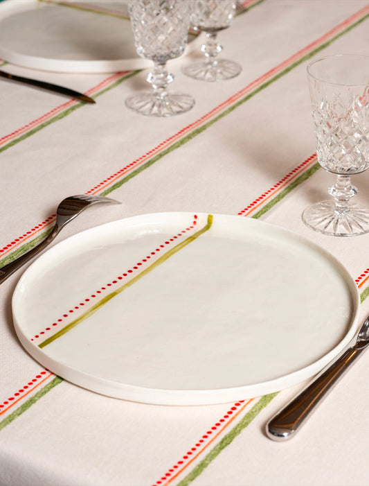 Grande assiette en porcelaine artisanale fabriquée en France, motif rayures colorées, sur nappe rayée