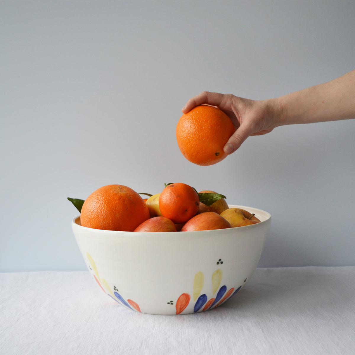Porcelaine fabriquée en France, grand saladier à motif Primavera rempli de fruits sur fond blanc