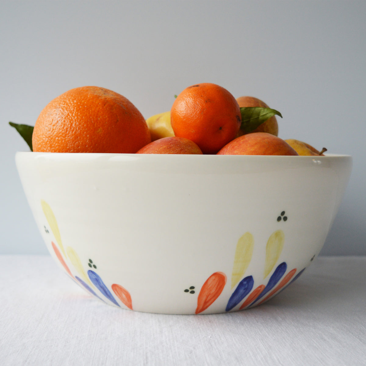 Porcelaine fabriquée en France, grand saladier à motif Primavera rempli de fruits sur fond blanc