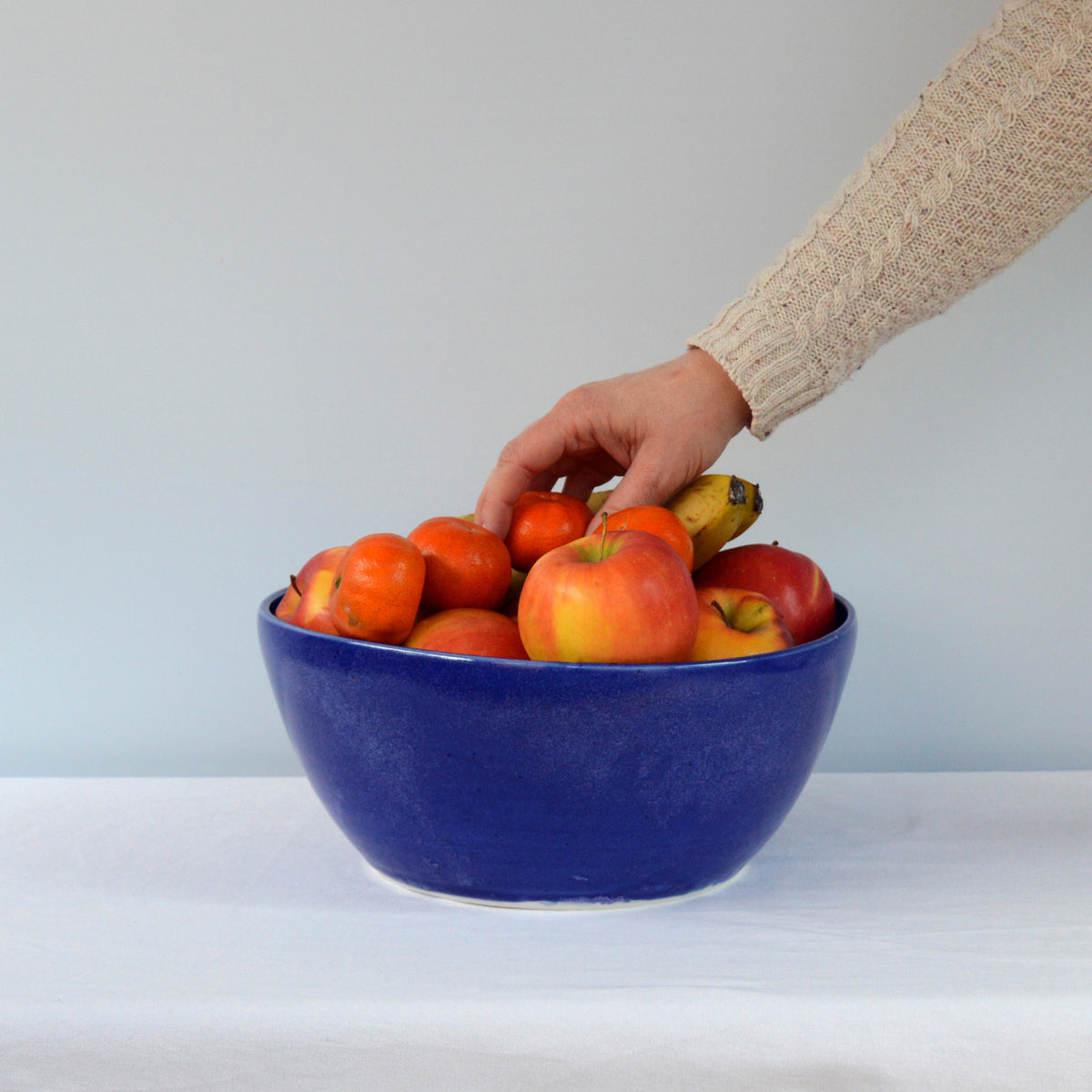Porcelaine fabriquée en France, grand saladier bleu Primavera rempli de fruits sur fond blanc