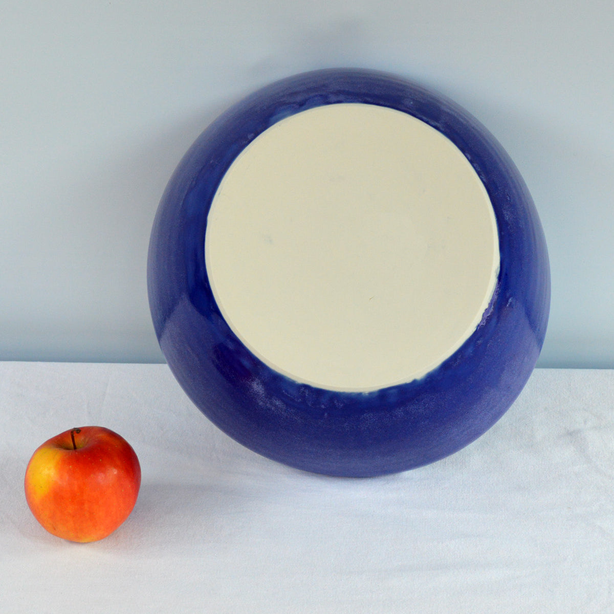 Porcelaine fabriquée en France, dos du grand saladier bleu Primavera sur fond blanc