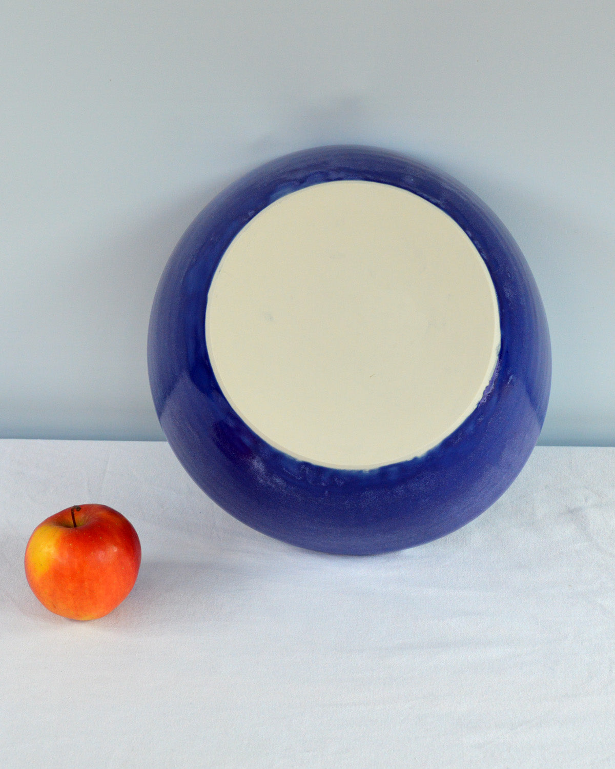 Porcelaine fabriquée en France, dos du grand saladier bleu Primavera sur fond blanc