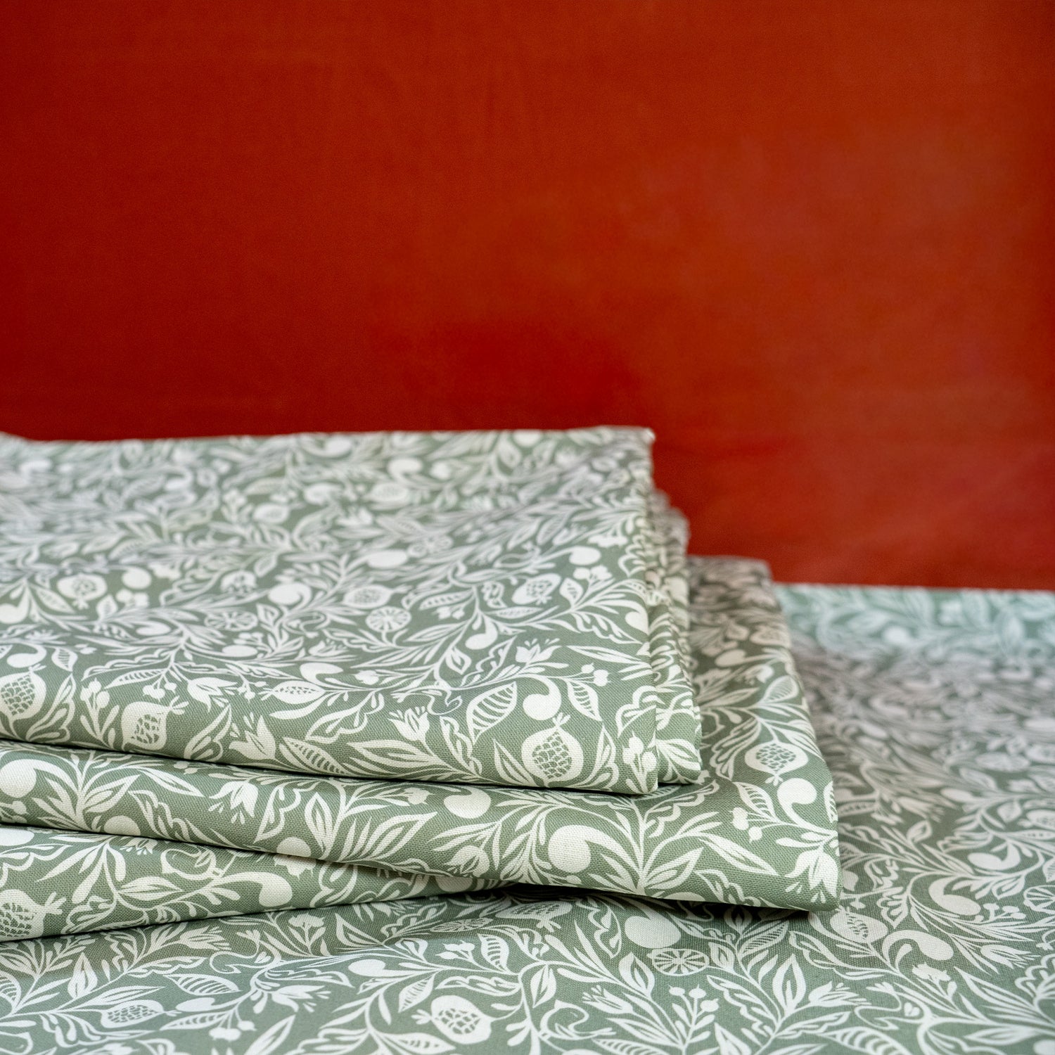 Pile de nappes vertes et blanches, fabriquées en France, en coton et lin certifié Oeko Tex, motif floral polychrome Alsace