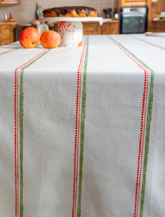Nappe en coton et lin fabriquée en France à rayures vertes, oranges et rouges avec un compotier et des pommes dans le fond