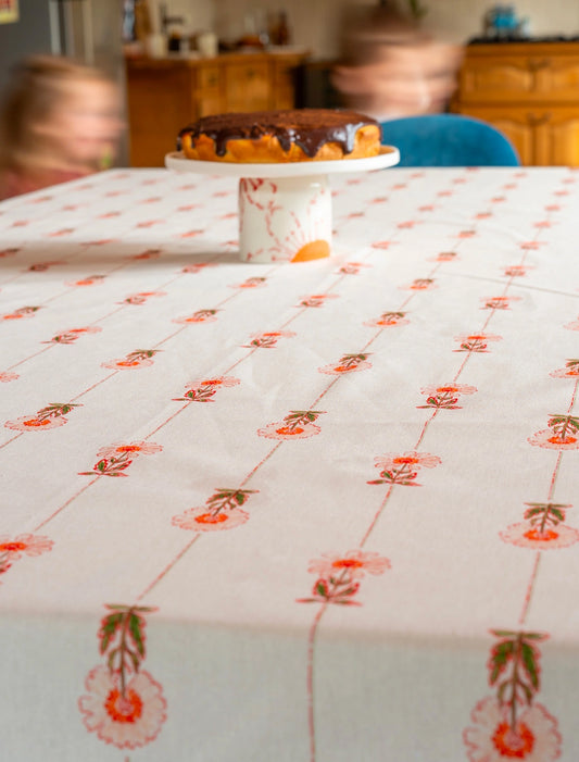 Nappe fabriquée en France avec un motif de rayures et de fleurs des champs, avec un compotier en porcelaine dans le fond