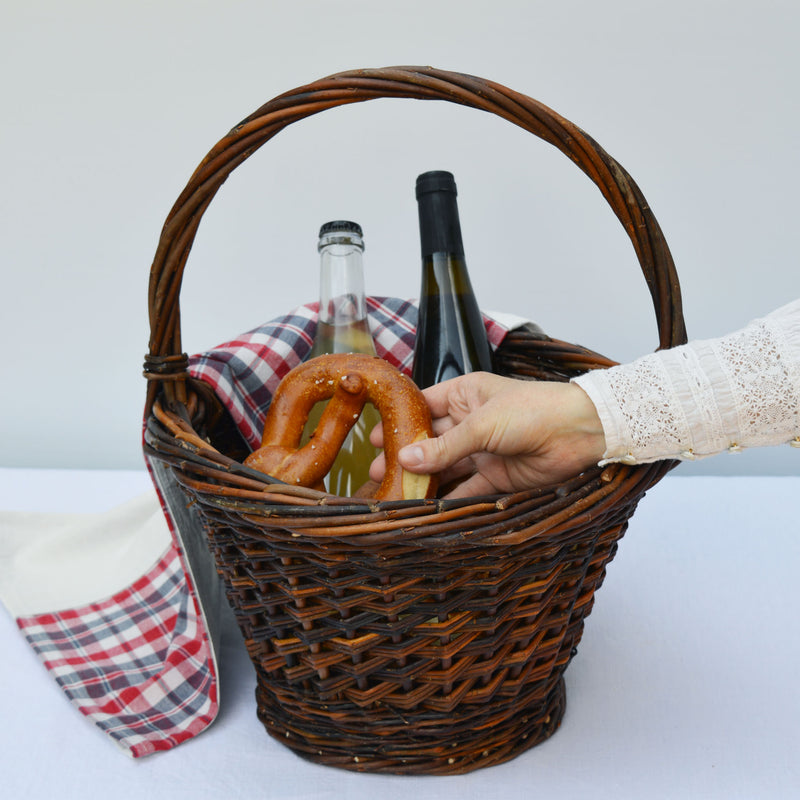 Panier rond en osier, fabriqué en France artisanalement, en Alsace. Pique-nique, torchon en kelsch et lin, bouteilles de vin et bretzel.