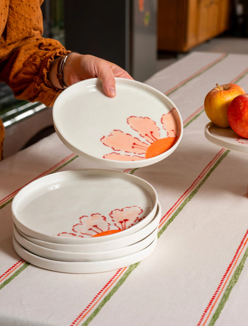 Assiette à dessert en porcelaine artisanale fabriquée en France, motif fleurs des champs colorées, pile d'assiette et nappe rayée