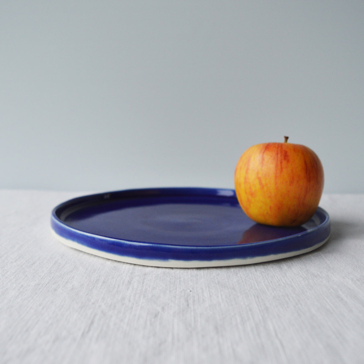 Porcelaine fabriquée en France, assiette à dessert bleue sur fond blanc