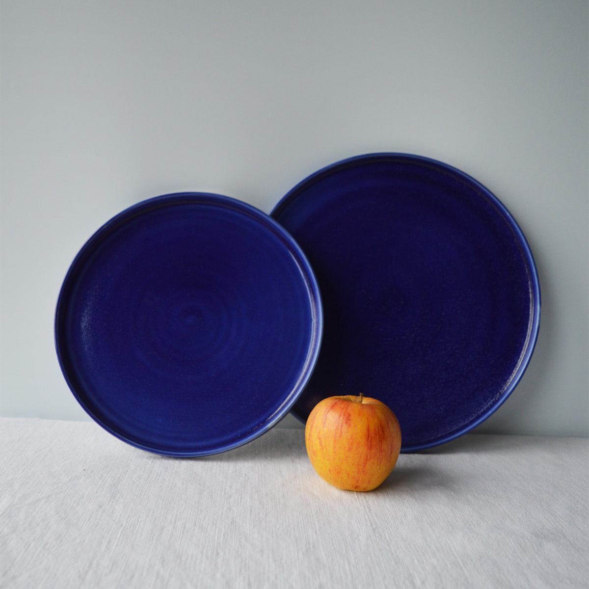 Porcelaine fabriquée en France, assiette à dessert et grande assiette bleues sur fond blanc