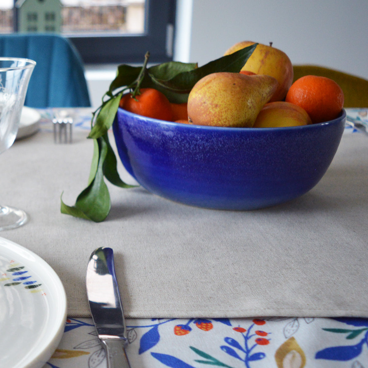 Porcelaine fabriquée en France, petit saladier bleu rempli de fruits sur une table dressée Maison Primavera