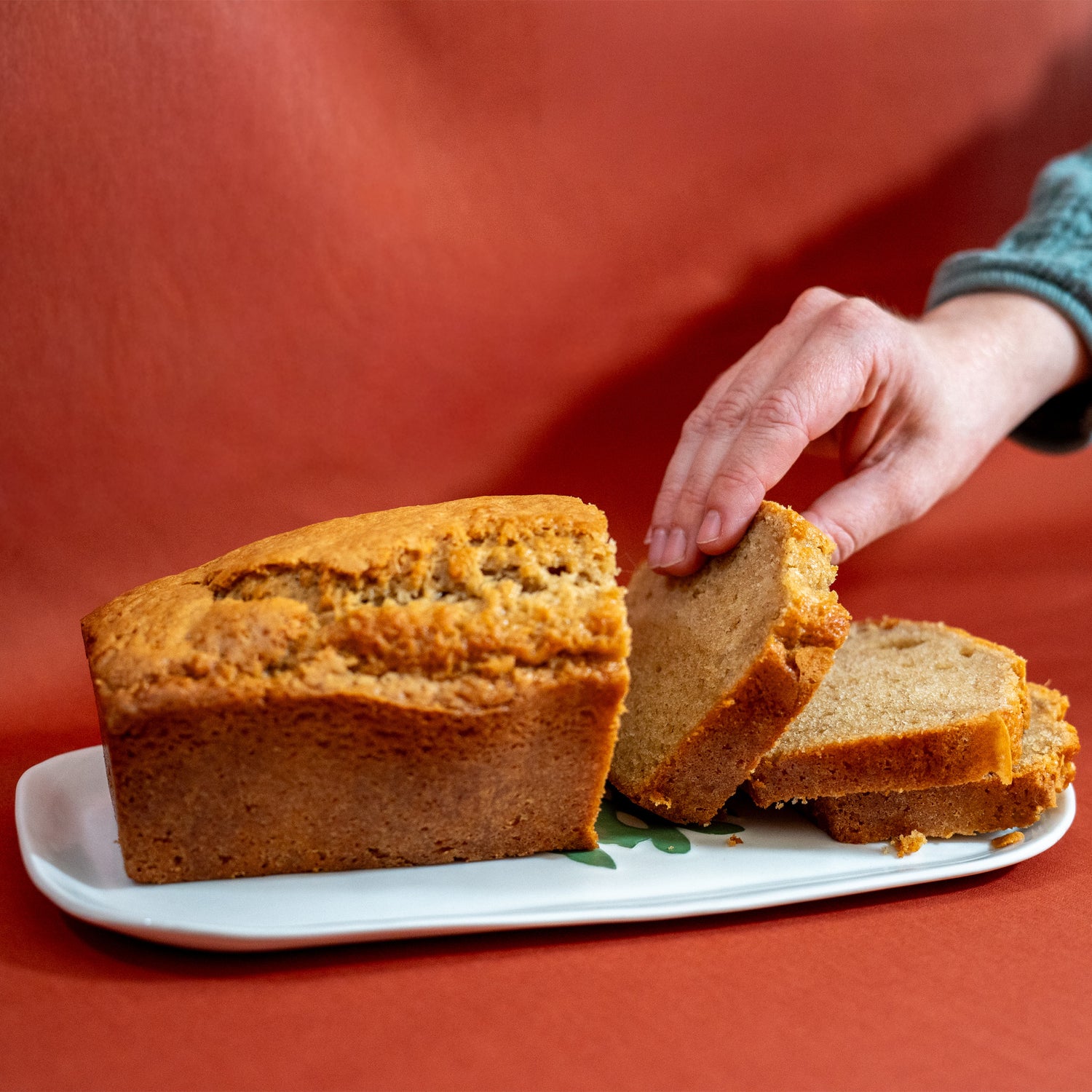 Plat à cake en porcelaine, fabriqué en France, artisanal, blanc à motif vert de cœur alsacien, gâteau aux épices posé dessus