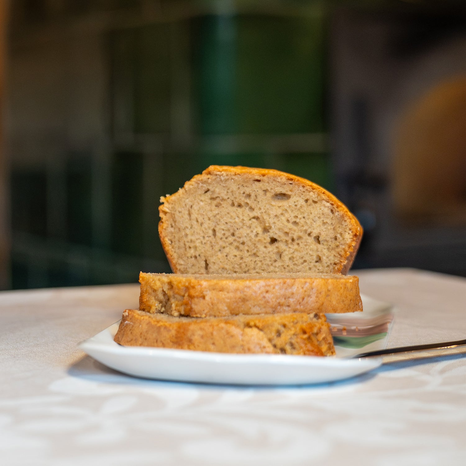 Plat à cake en porcelaine, fabriqué en France, artisanal, blanc à motif de montagne, couleurs pastels, gâteau aux épices tranché sur table dressée