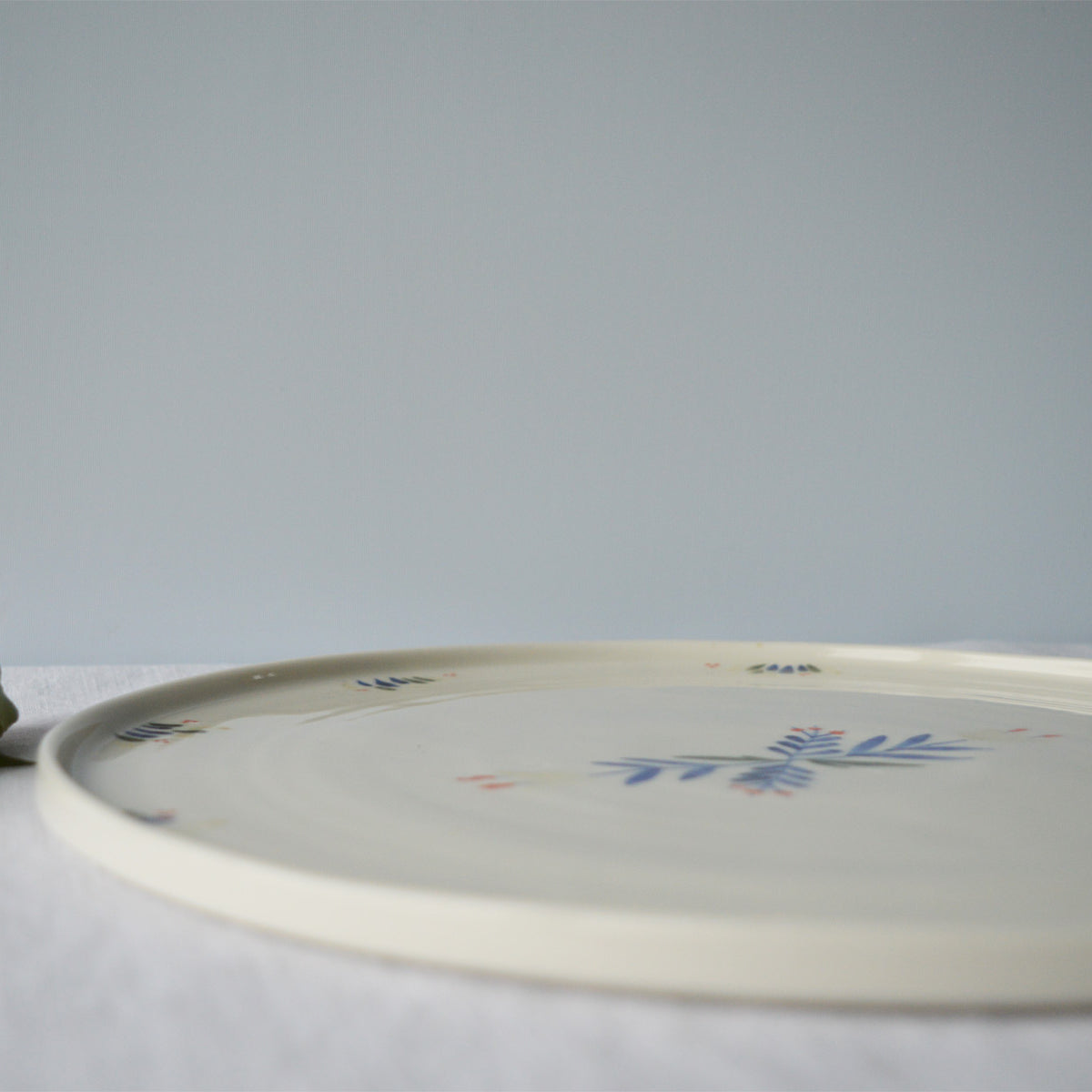 Porcelaine fabriquée en France, zoom sur plat de service rond à motif Primavera sur fond blanc
