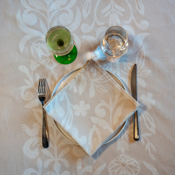 Serviette de table beige et blanche, fabriquée en France, en coton et lin, motif floral, arbre de vie alsacien, verres et couverts sur nappe