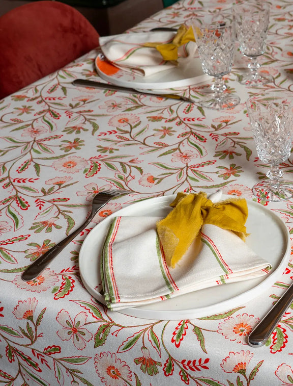 Serviettes de table en coton et lin fabriquées en France avec un motif à rayures colorées, sur table dressée avec vaisselle artisanale