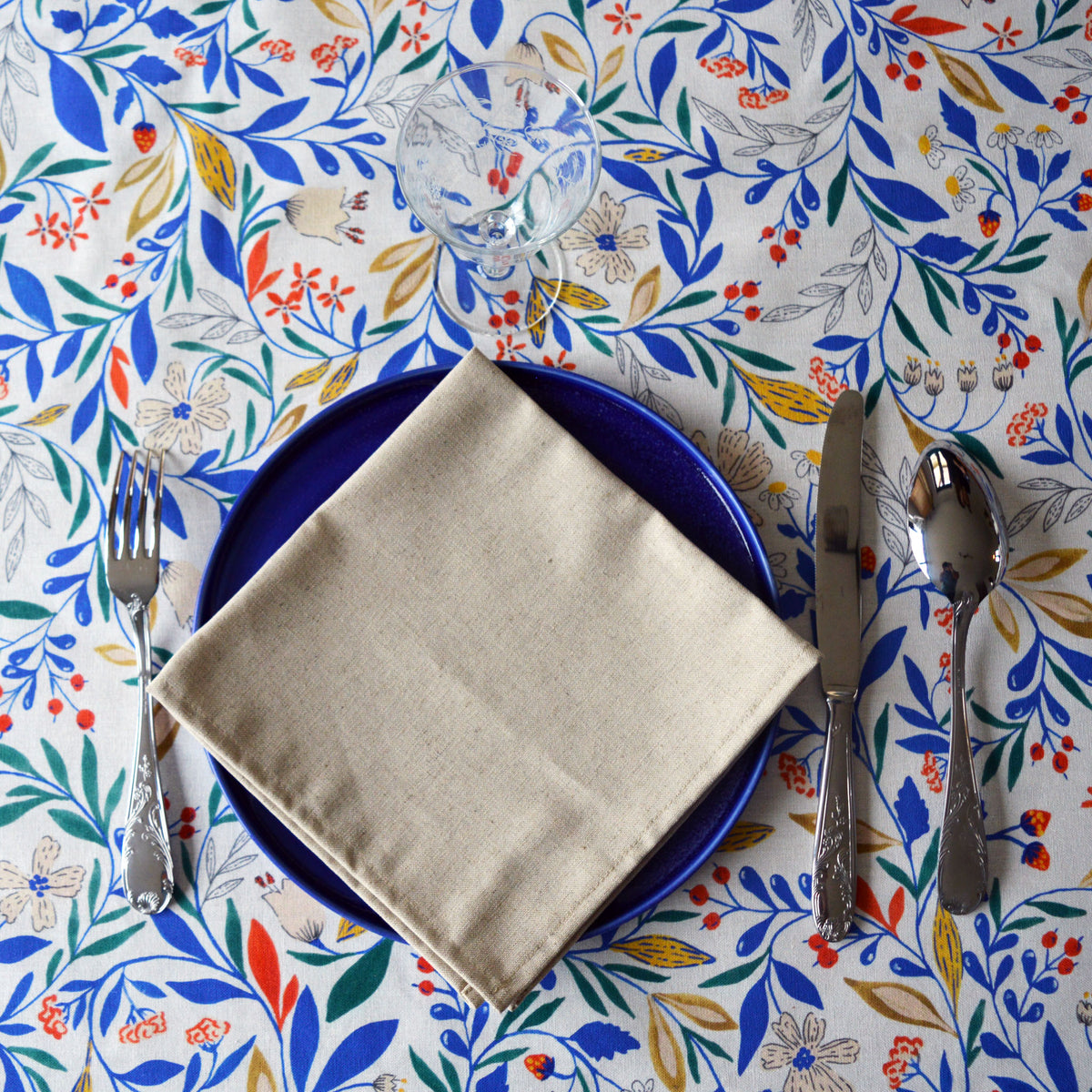 Serviette beige naturel en coton lin fabriquée en France sur assiette bleue porcelaine et nappe fleurie