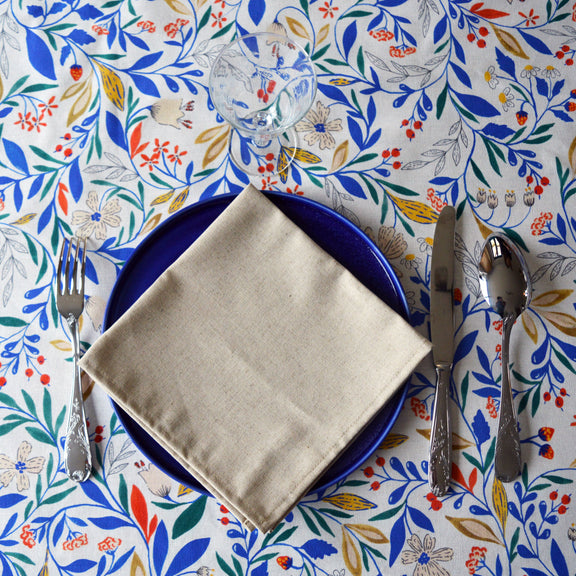 Serviette beige naturel en coton lin fabriquée en France sur assiette bleue porcelaine et nappe fleurie