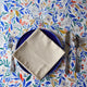 Serviette beige naturel en coton lin fabriquée en France sur assiette bleue porcelaine et nappe fleurie