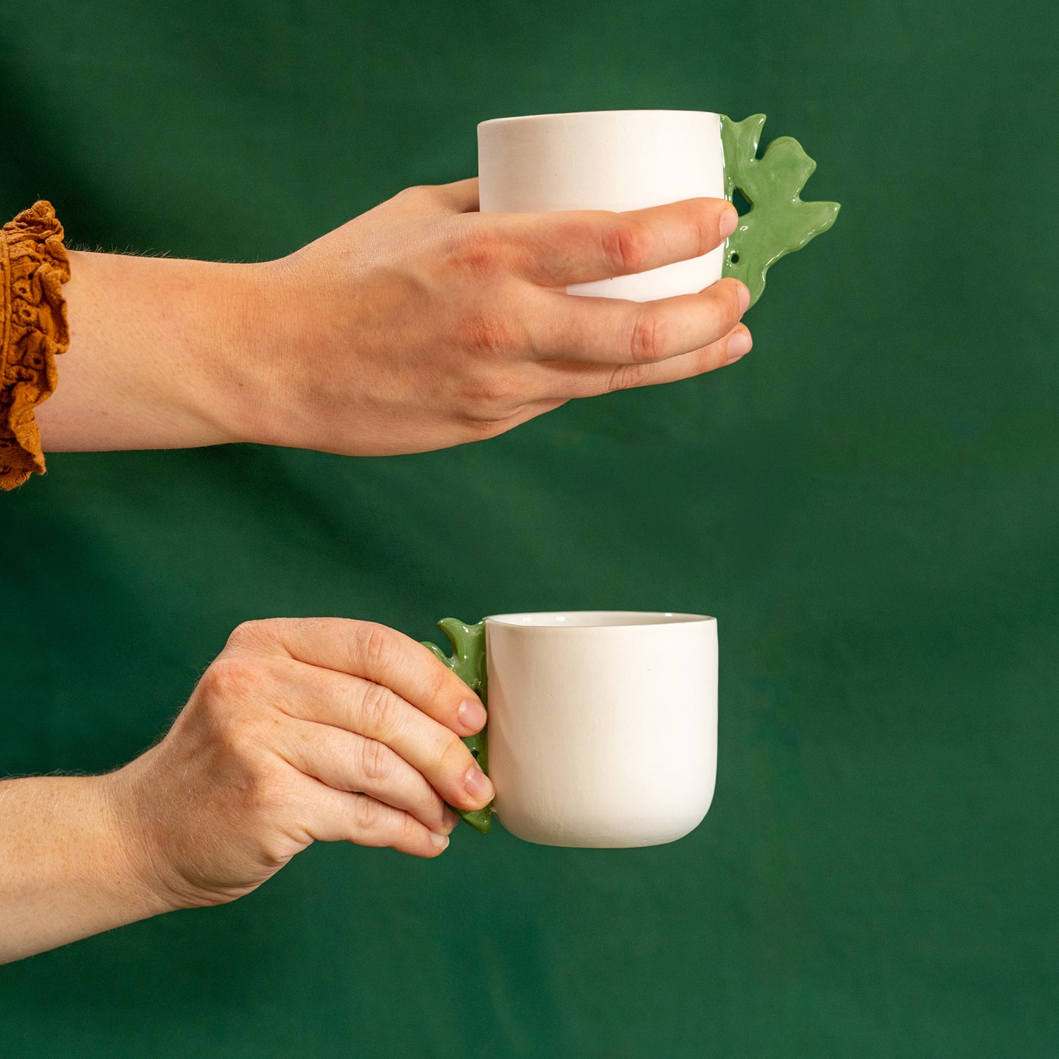 2 tasses à café artisanales fabriquées en France, en porcelaine blanche avec une anse verte motif cœur alsacien, tenues à la main